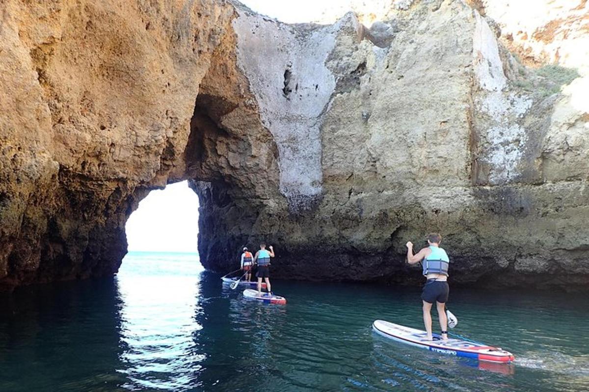 tre persone su tavole da paddle in acqua vicino a una grotta