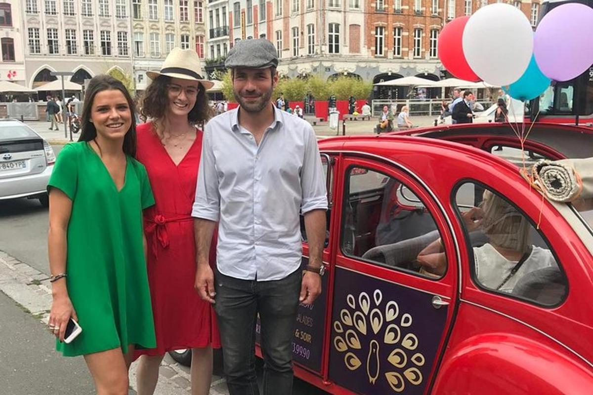 a man and two women standing next to a red car