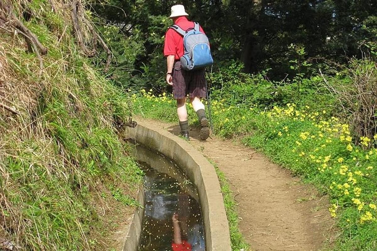um homem caminhando por um caminho de terra perto de um lago