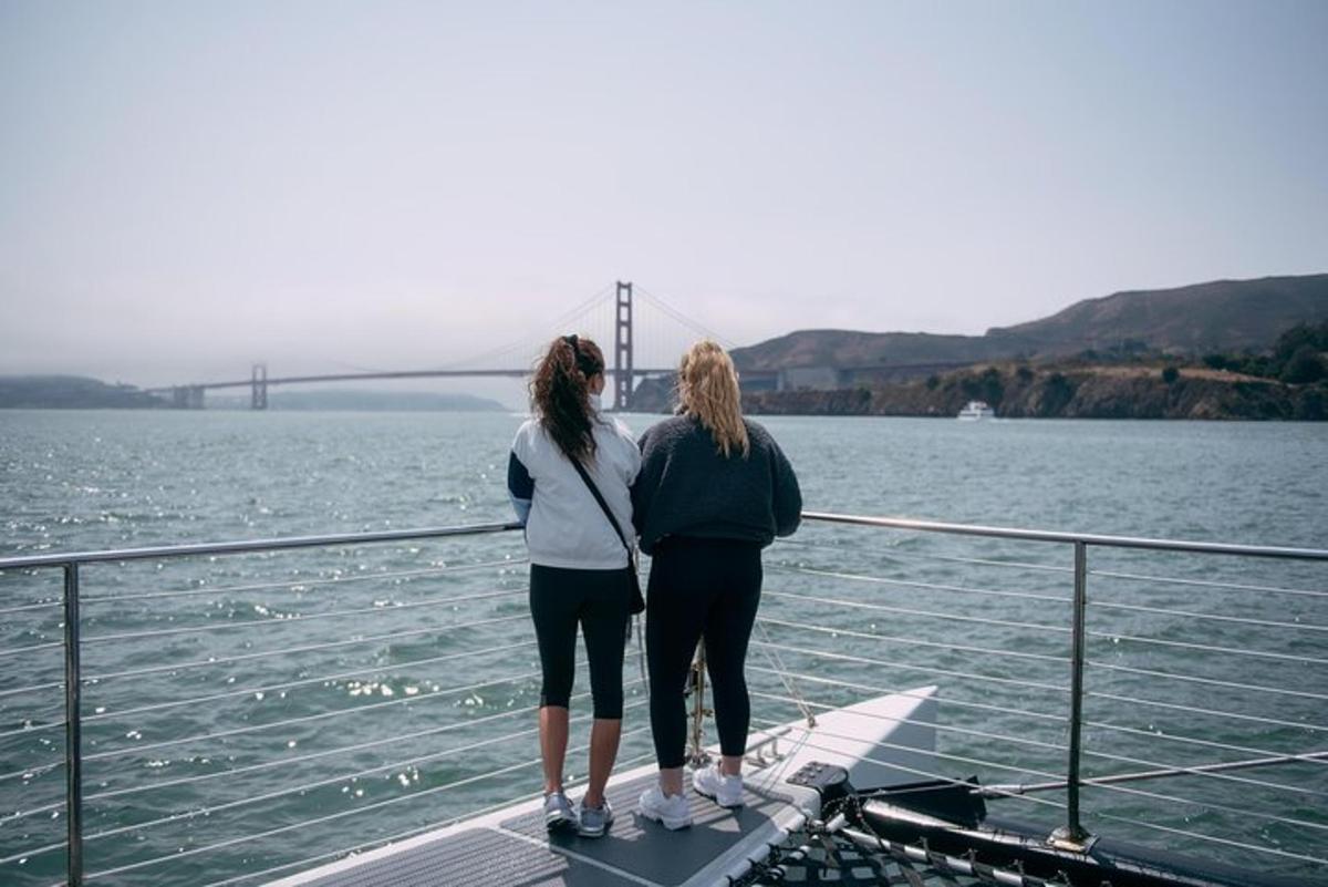 Dos mujeres de pie en un bote en el agua con un puente