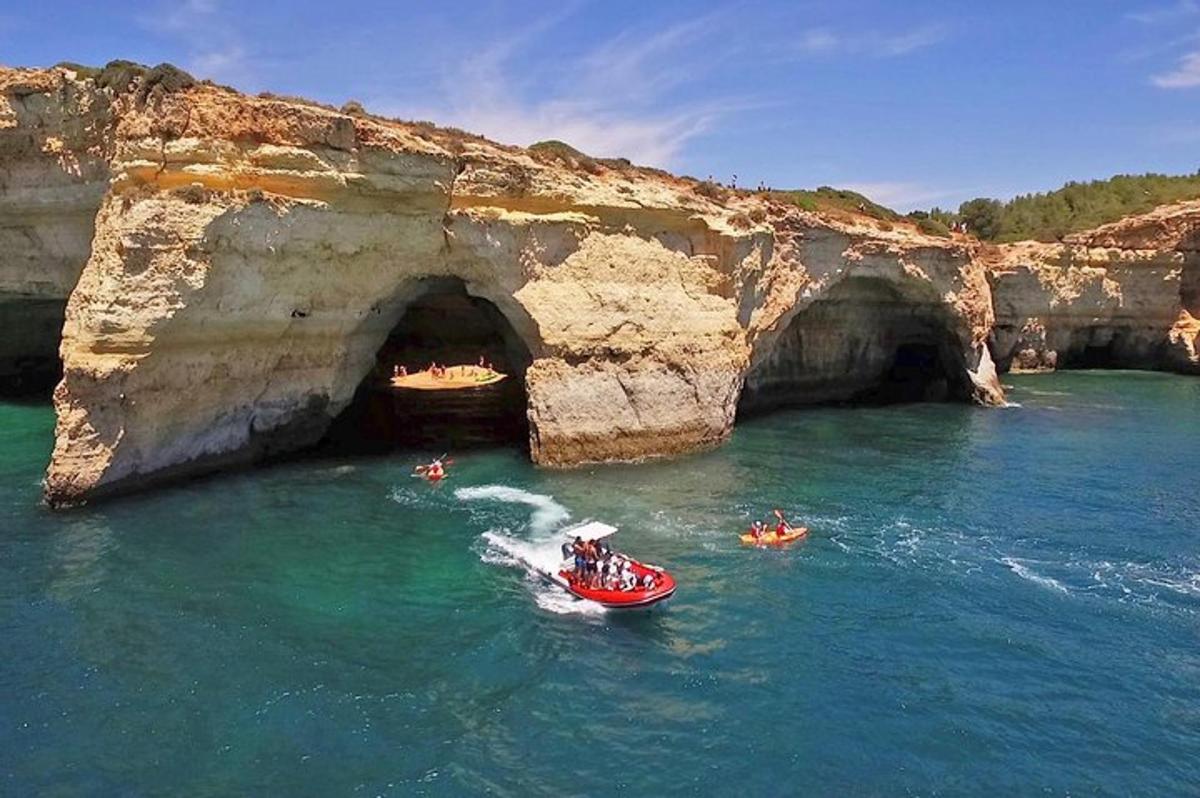 a group of people in a boat in the water near a cave