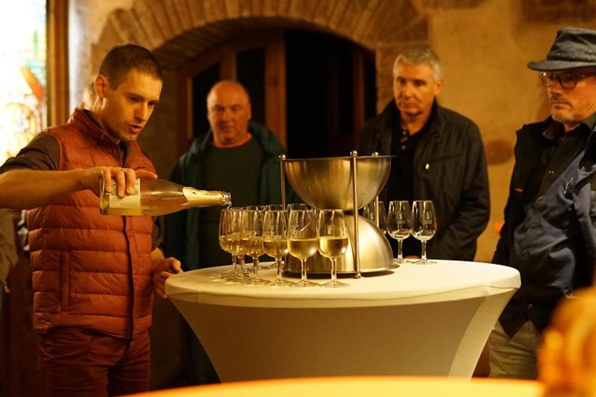 a man pouring wine into glasses on a table