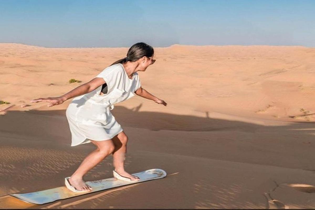 a woman standing on a surfboard in the desert