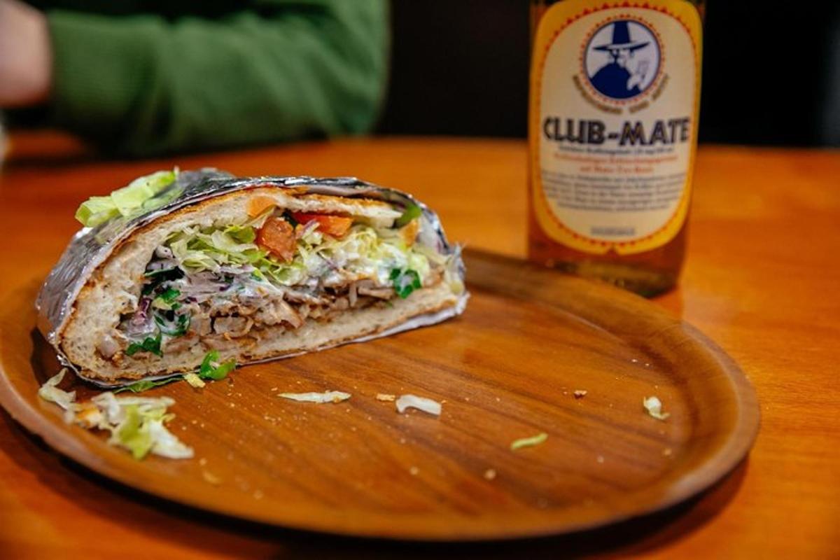 un entrepà en un plat al costat d'una ampolla de cervesa