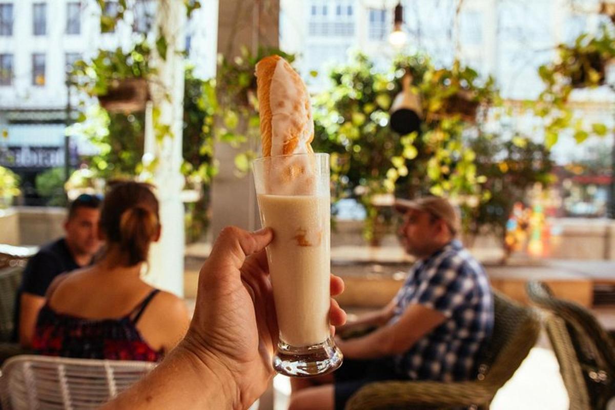 una persona che tiene in mano un drink con un pezzo di pane