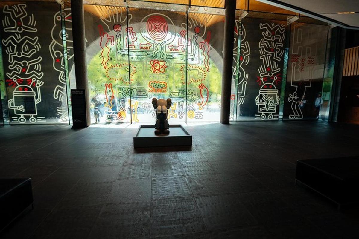 a statue in a room with a wall with graffiti