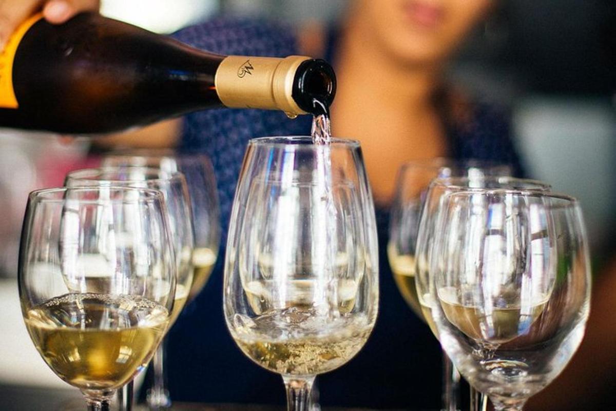 osoba nalewająca wino do szeregu kieliszków