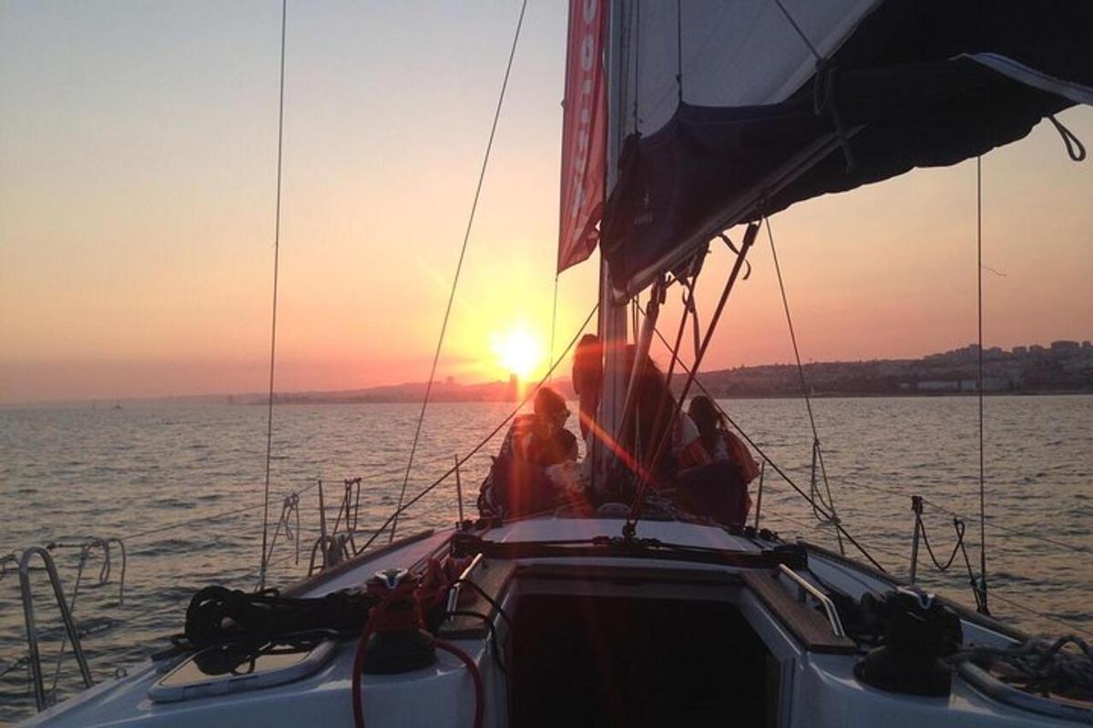 two people on a sailboat in the water at sunset