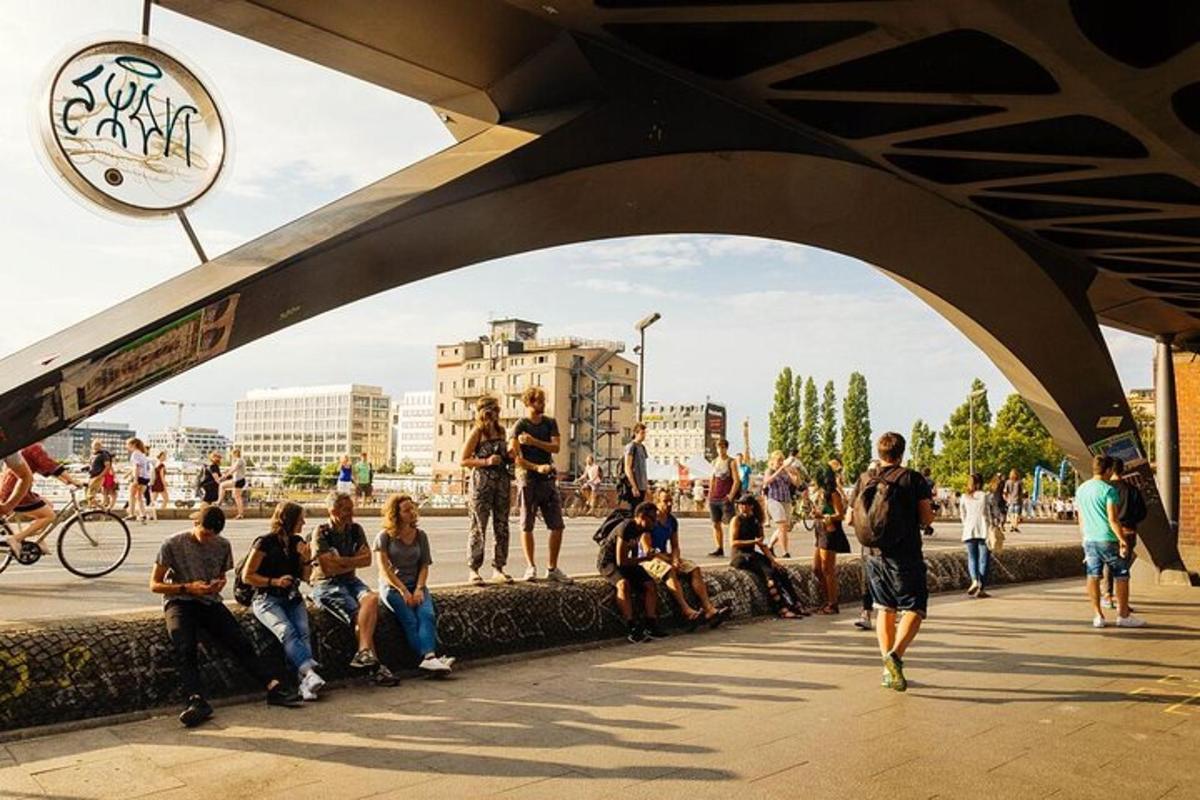 skupina lidí sedících na chodníku pod mostem