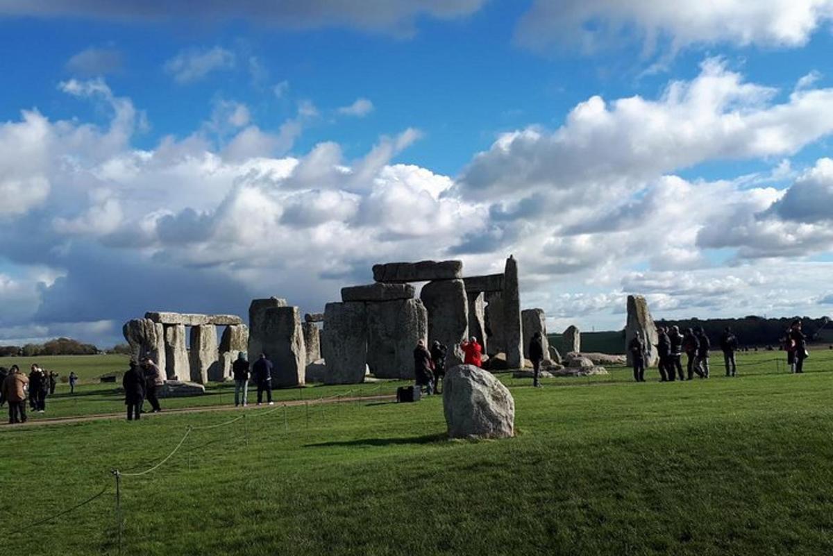 um grupo de pessoas em pé ao redor de Stonehenge em um campo