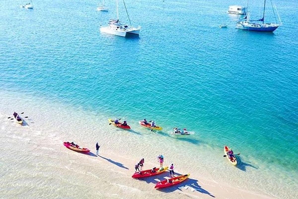 a group of people on a beach with boats in the water
