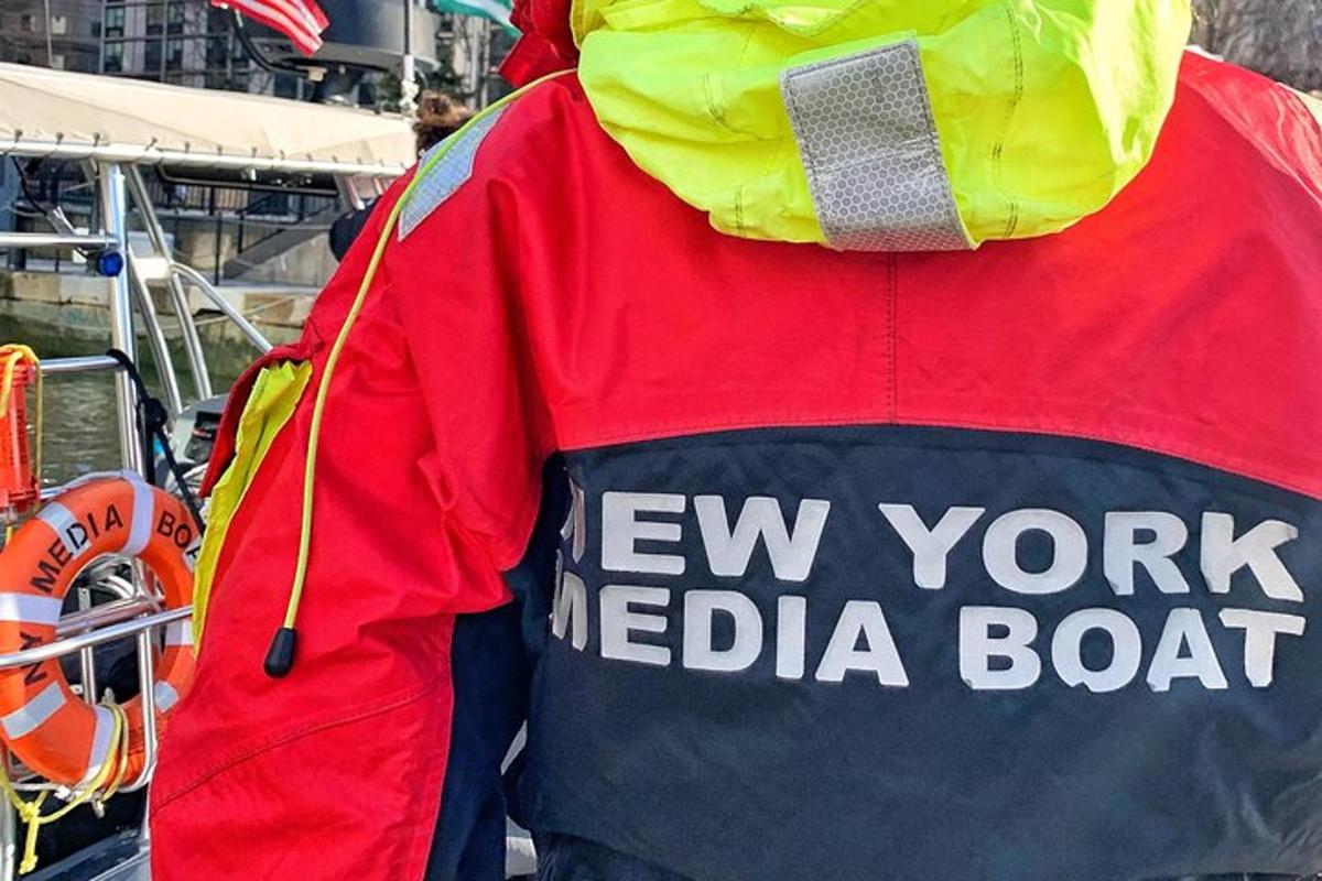 a person wearing a red and yellow jacket with the words new york media boat