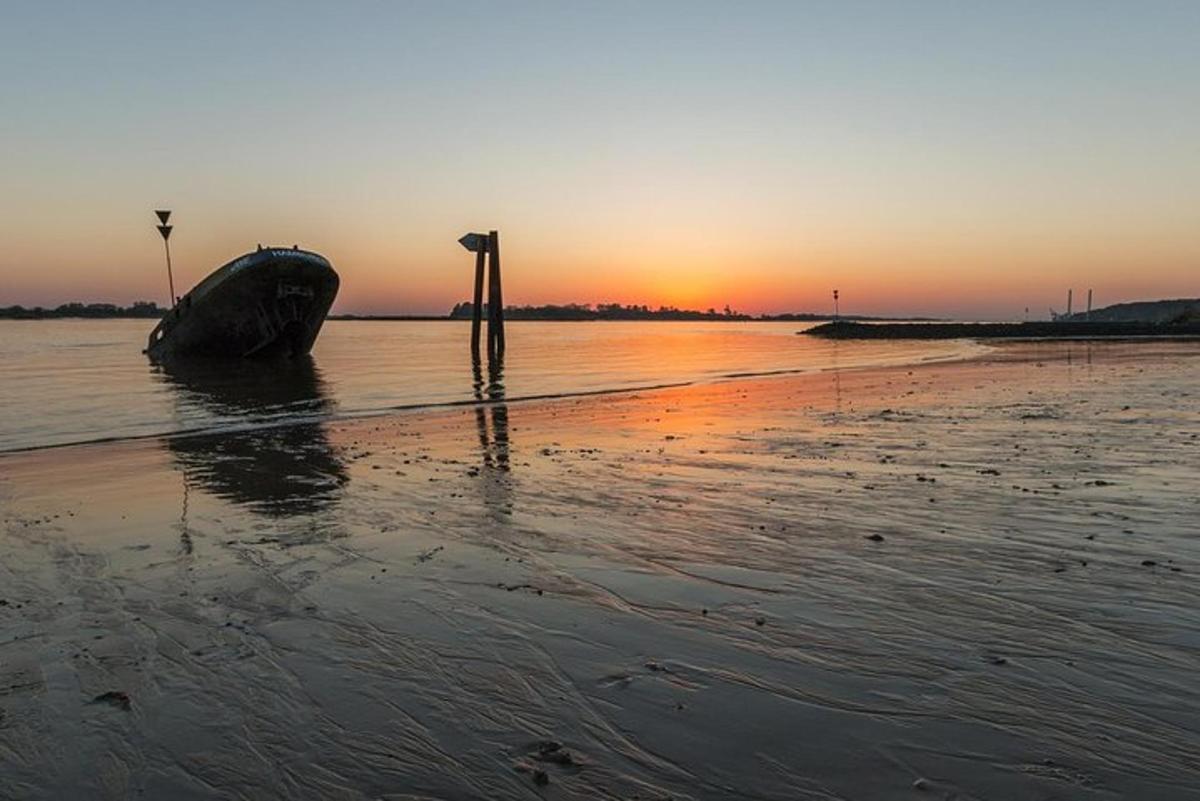 a boat sitting on the beach at sunset