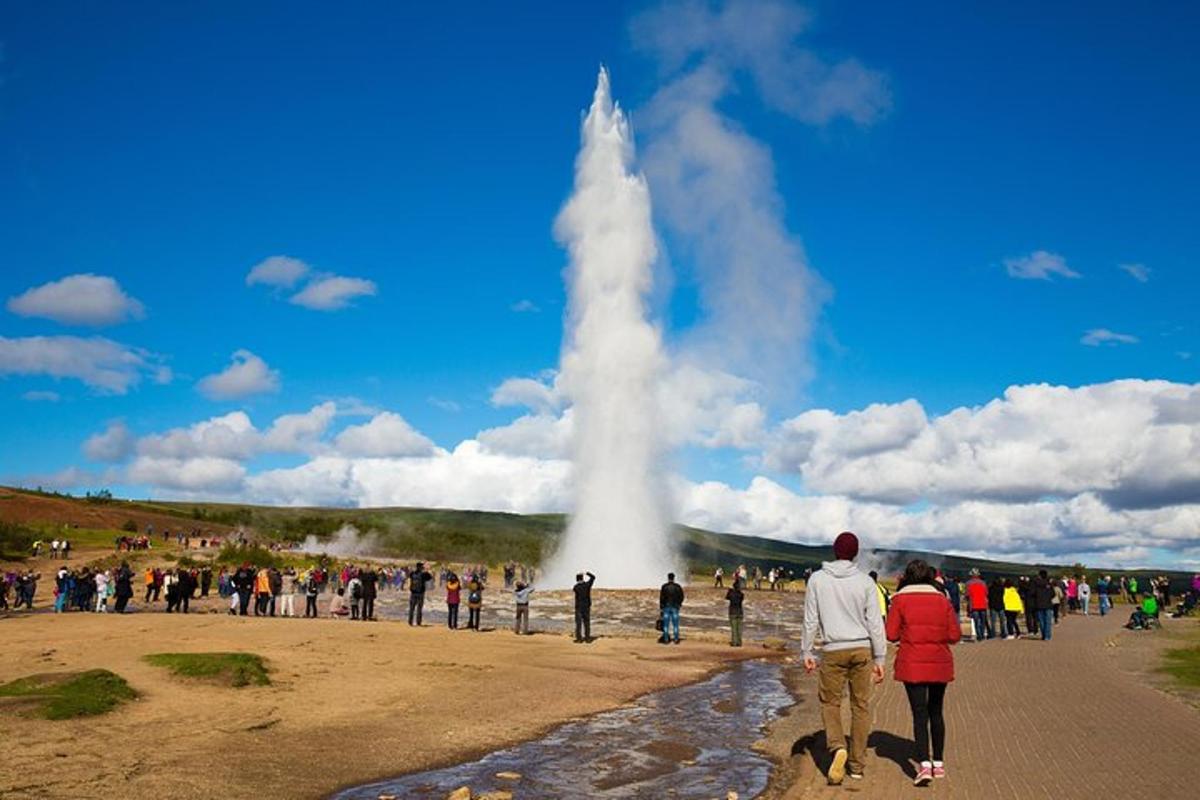 eine Gruppe von Menschen steht um einen Geysir herum