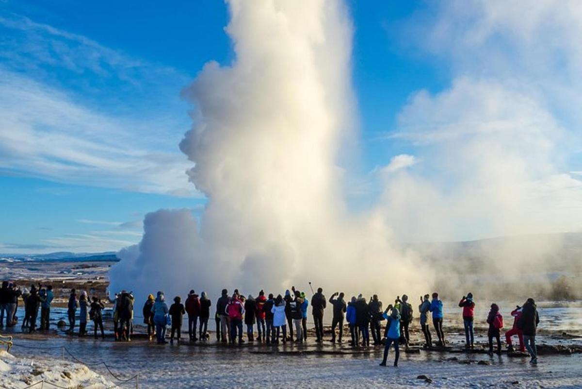 eine Gruppe von Menschen steht vor einem Geysir