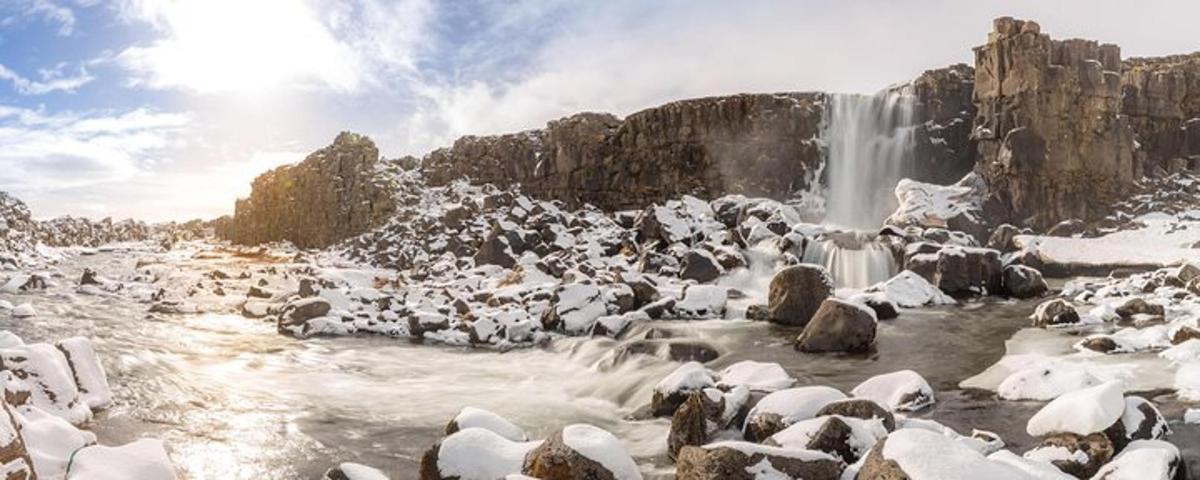 ein Fluss mit einem Wasserfall und Schnee auf den Felsen