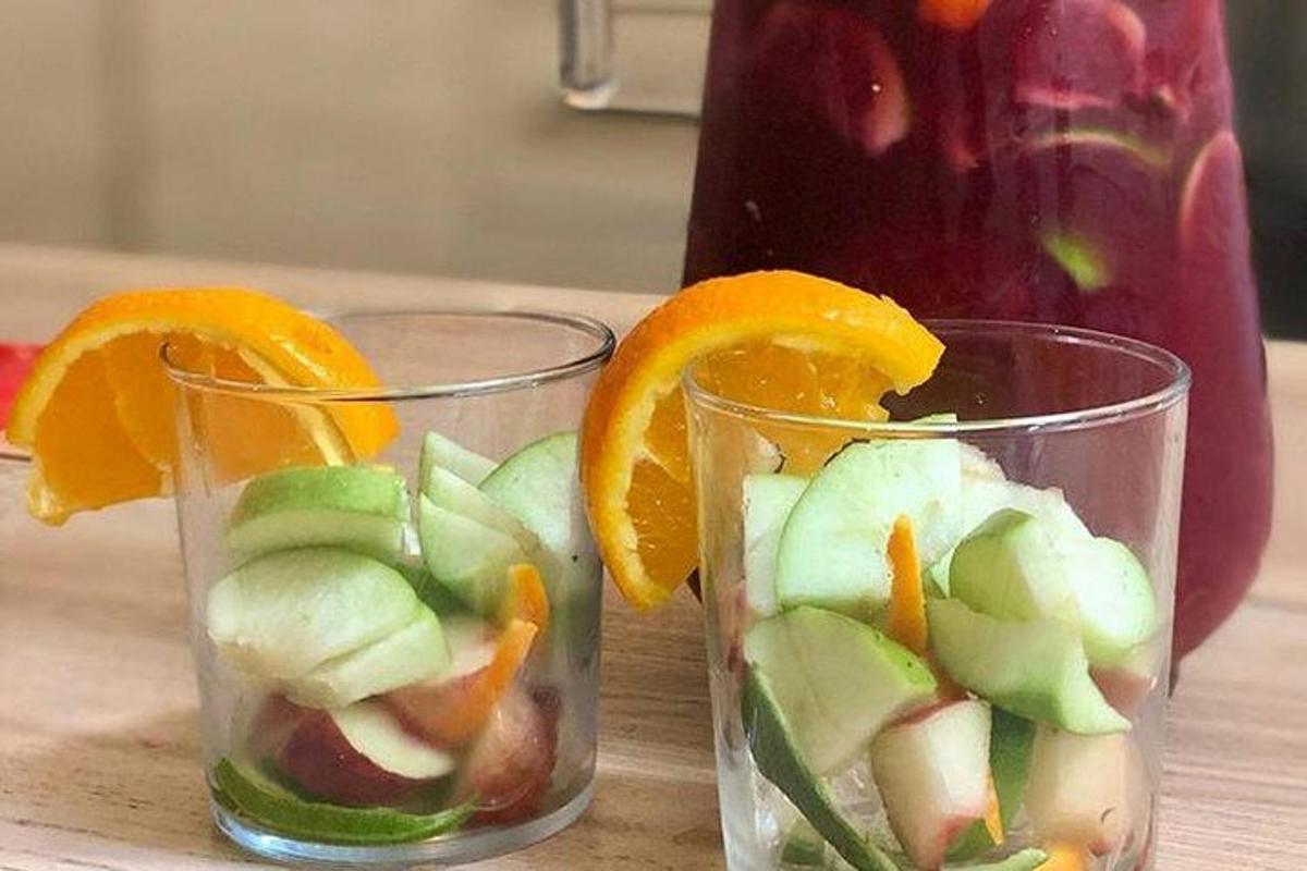 two glasses filled with fruit and vegetables on a table