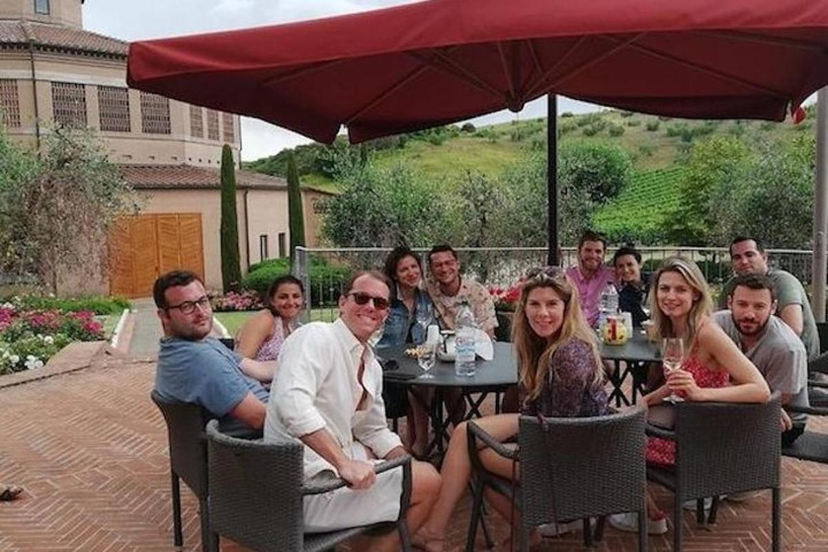 Un grupo de personas sentadas en una mesa bajo una sombrilla.