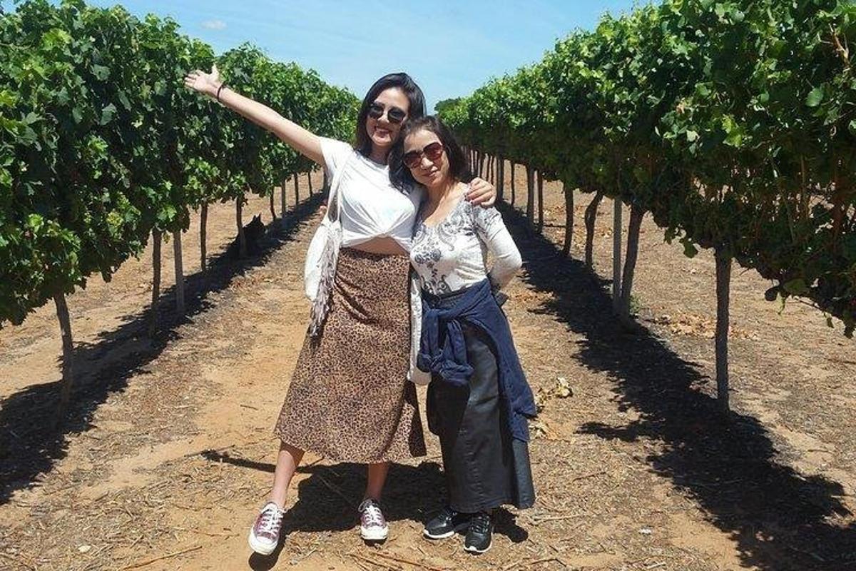 two women standing in a vineyard posing for a picture