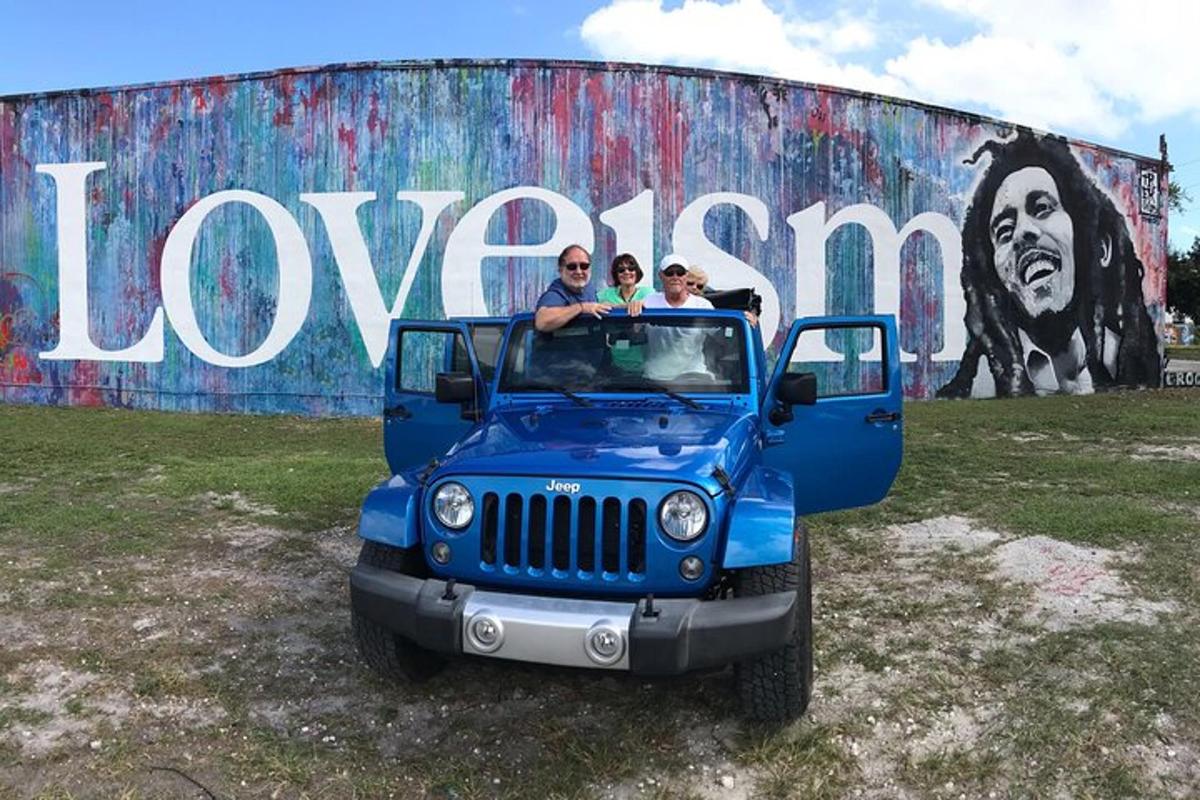tiga orang menaiki jip biru di hadapan mural