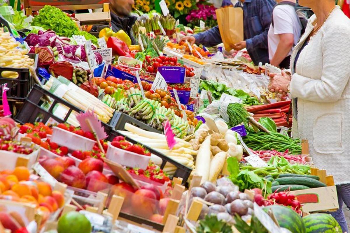 a woman standing in front of a market filled with fruits and vegetables