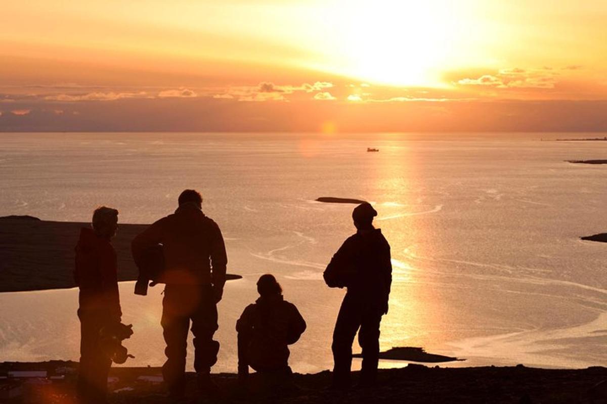 un gruppo di persone in piedi sulla spiaggia al tramonto