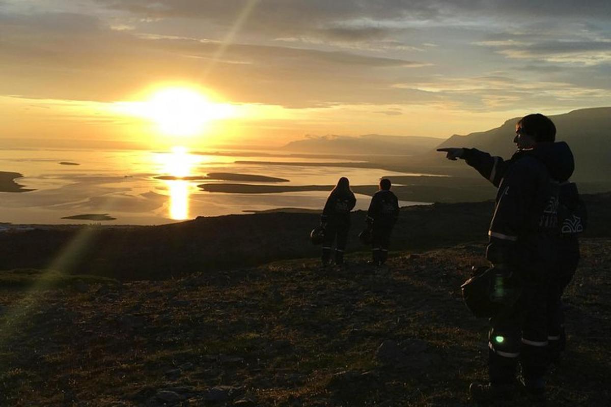 un gruppo di persone in piedi sulla cima di una montagna al tramonto
