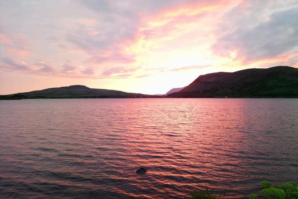 un tramonto su un grande specchio d'acqua con montagne