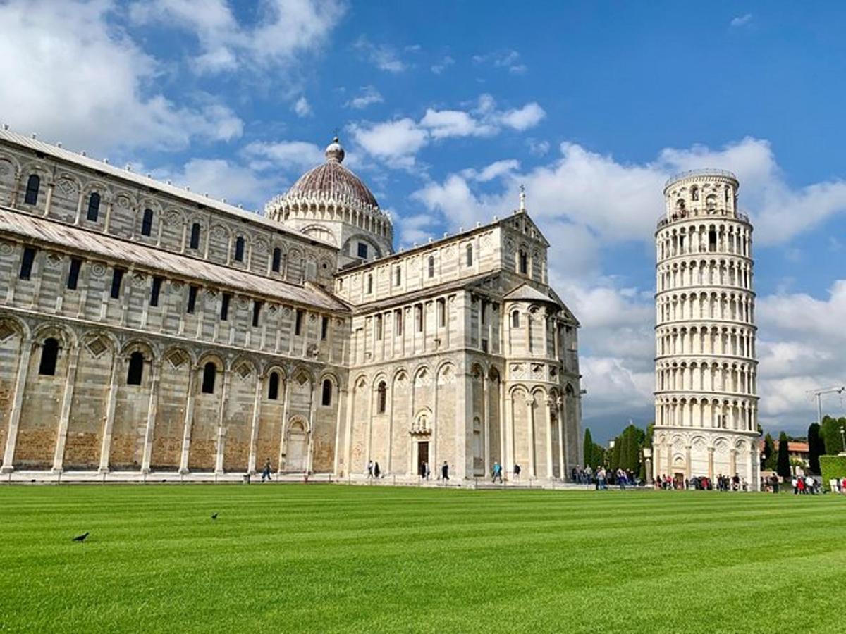 un gran edifici amb una torre inclinada i un camp verd