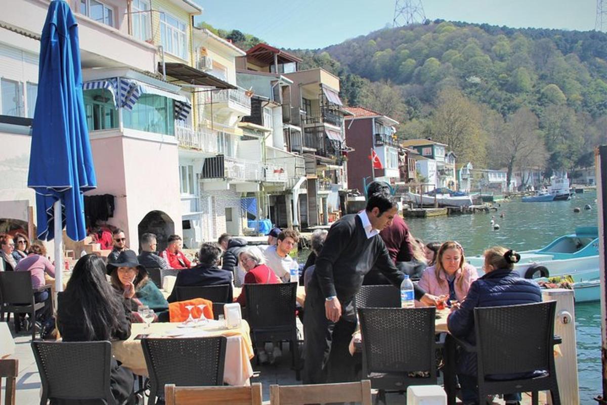 μια ομάδα ανθρώπων που κάθονται σε τραπέζια κοντά σε ένα υδάτινο σώμα