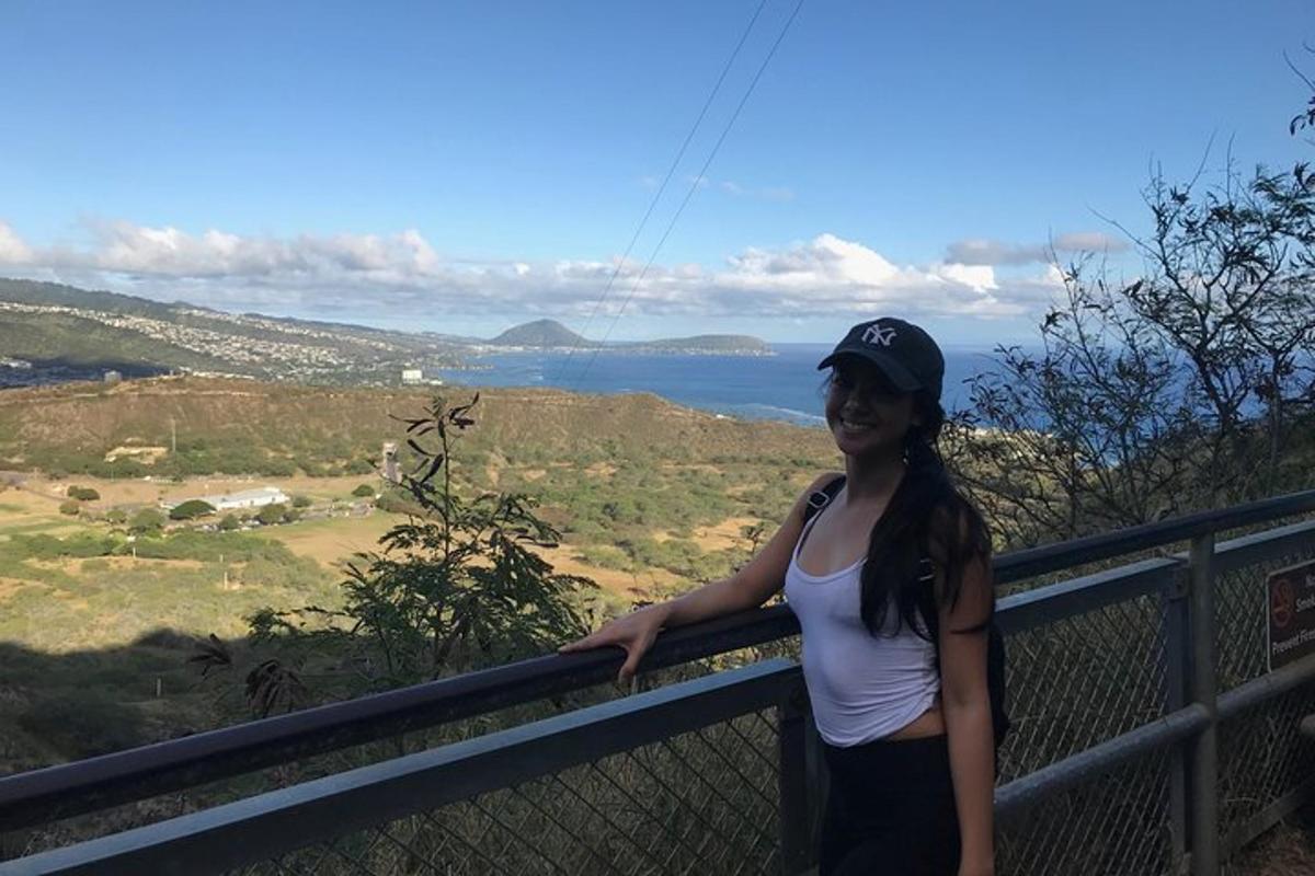 一位女士站在篱笆上，欣赏海景