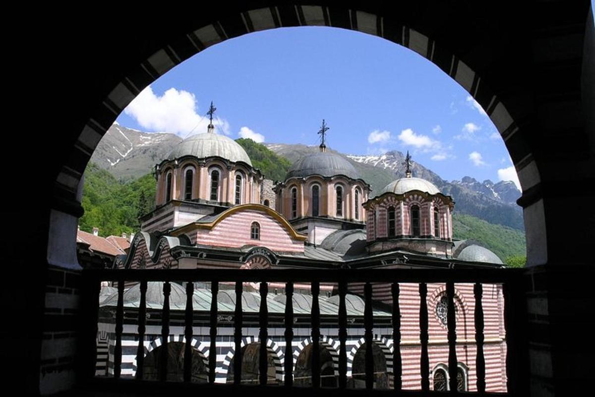 an archway view of a church with mountains in the background