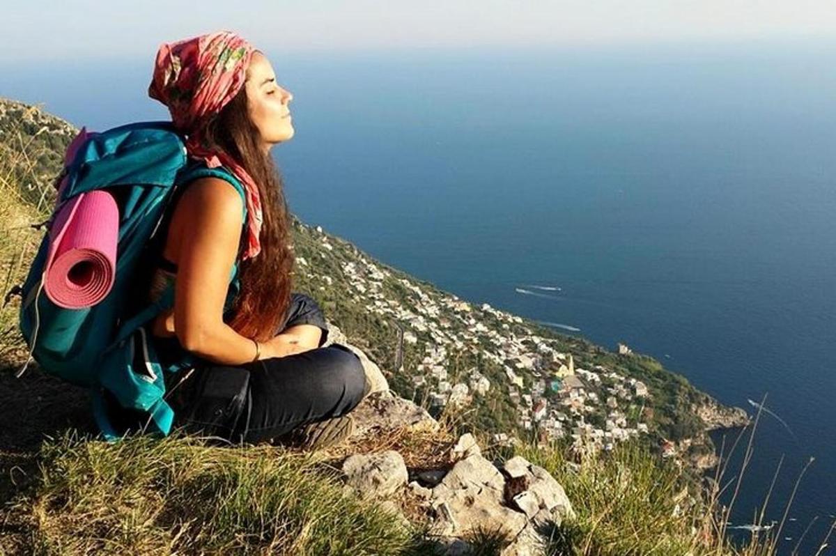 o femeie stând pe vârful unui deal cu un rucsac