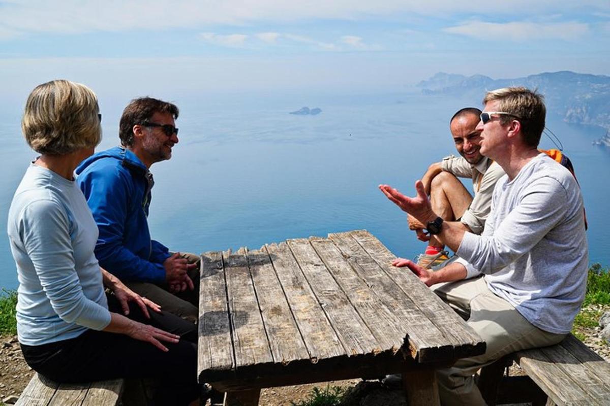 un grup de oameni așezați în jurul unei mese de picnic cu vedere la apă
