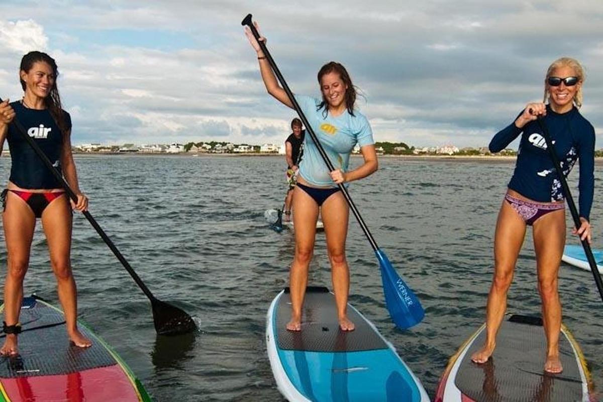 Tri dievčatá stoja na paddleboardoch na vode