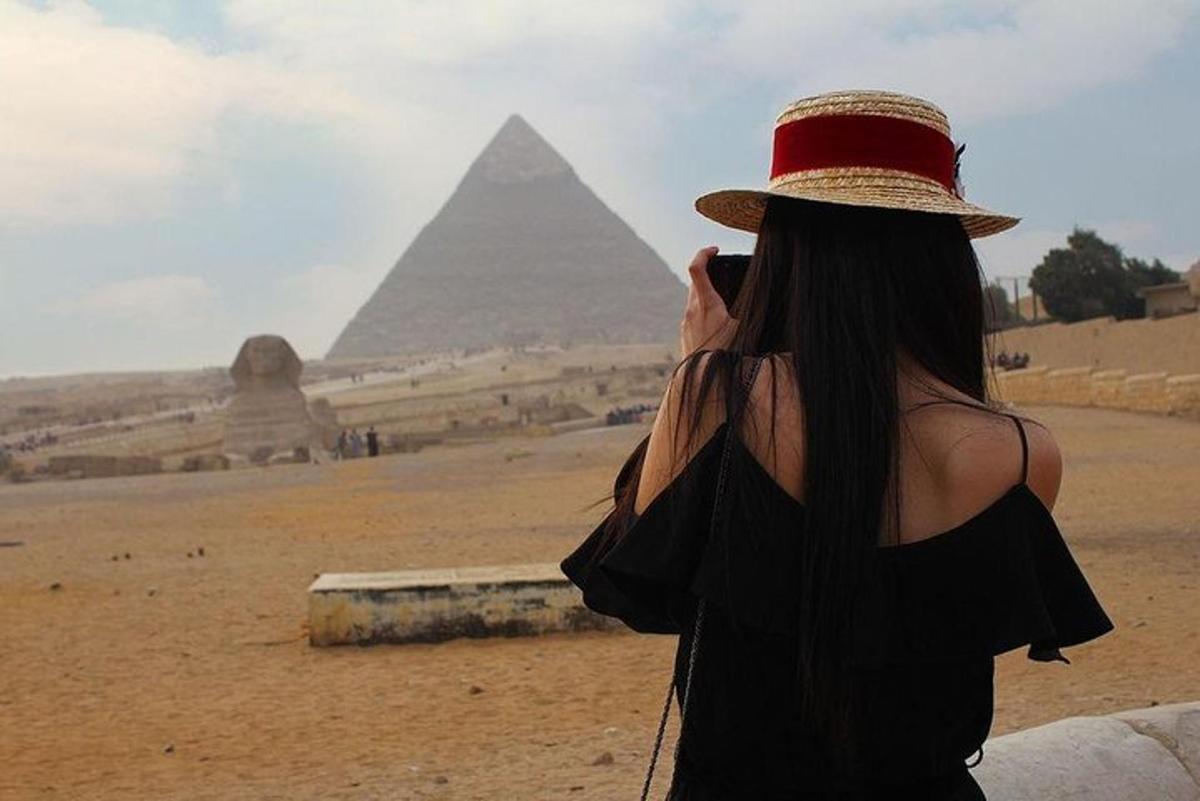 una donna con un cappello che scatta una foto delle piramidi