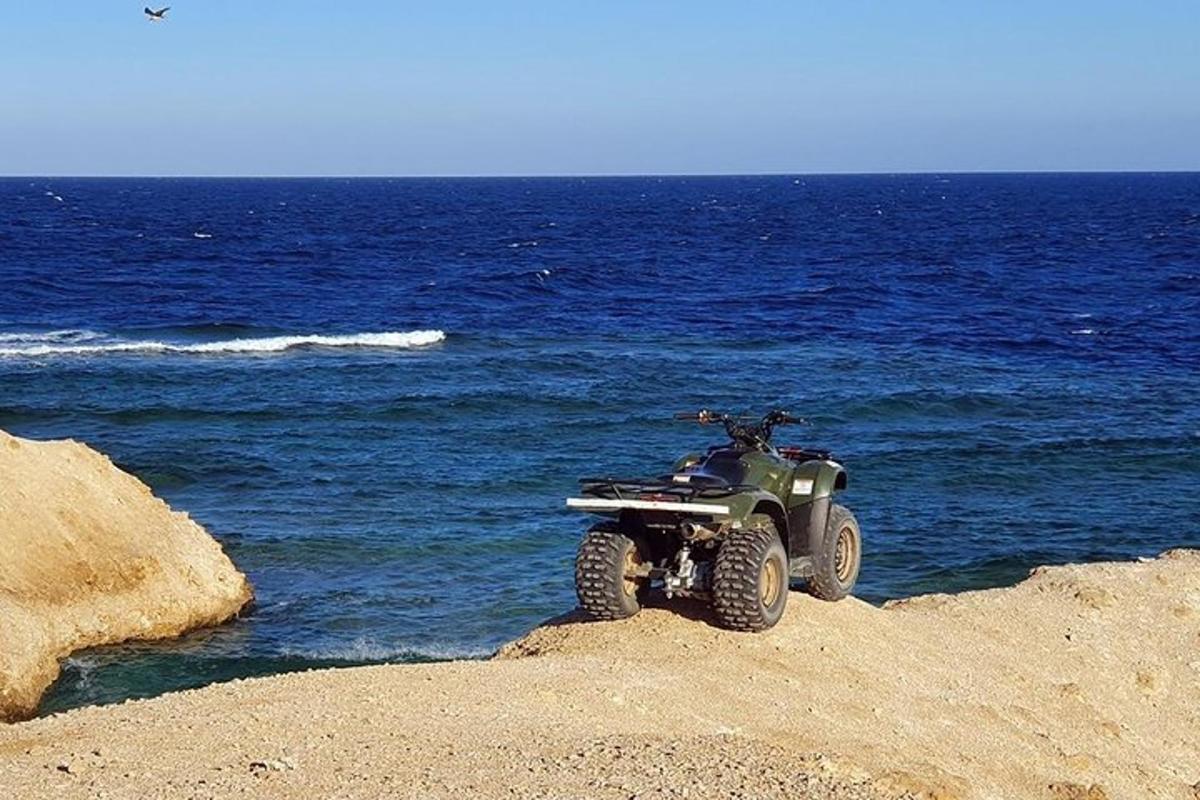 a four wheeler parked on a beach near the ocean