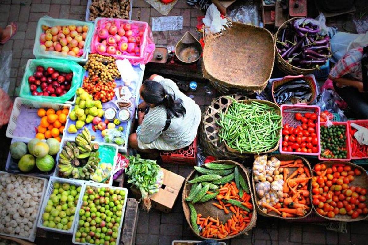 a woman sitting in front of a display of fruits and vegetables