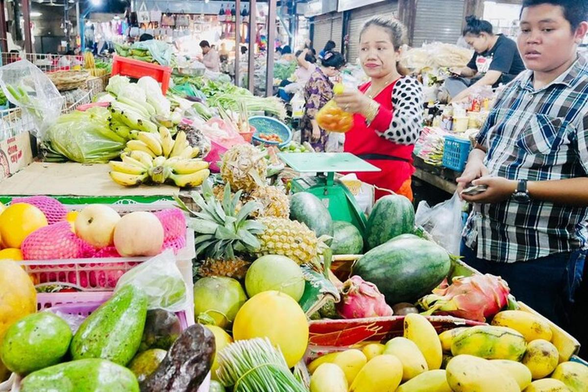 seorang lelaki dan wanita berdiri di pasar dengan buah-buahan dan sayur-sayuran