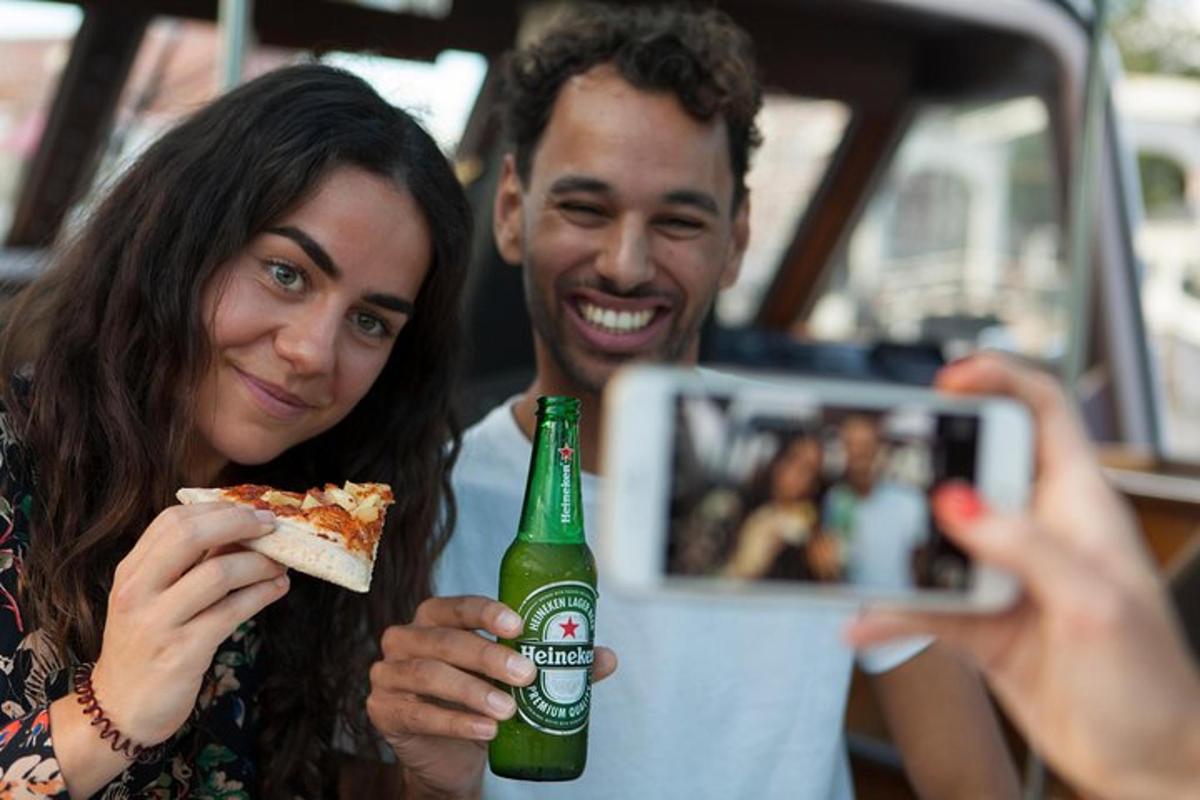 žena fotí muže jícího kousek pizzy