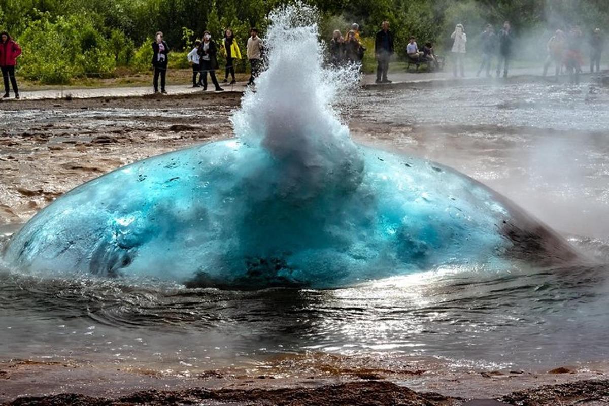 Un objeto azul en el agua con gente caminando alrededor.