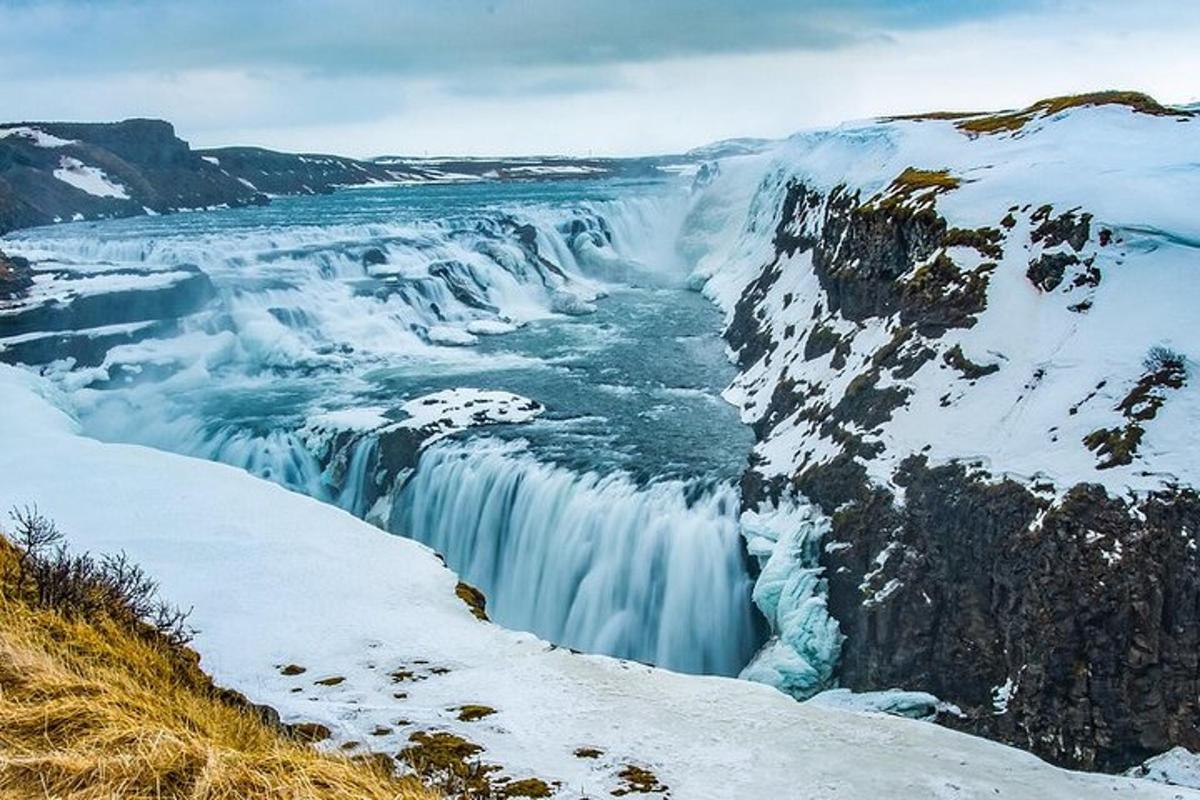 Una cascada congelada con nieve en la ladera de una montaña.