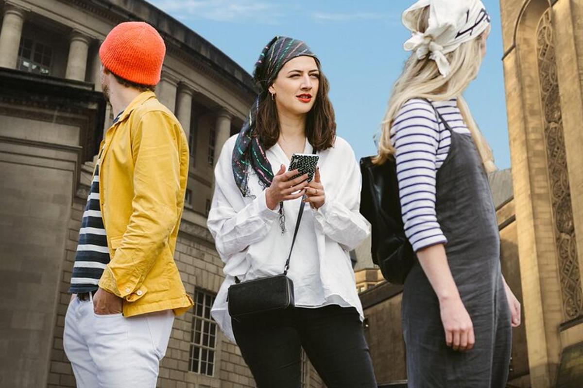 three women standing on a street looking at a cell phone