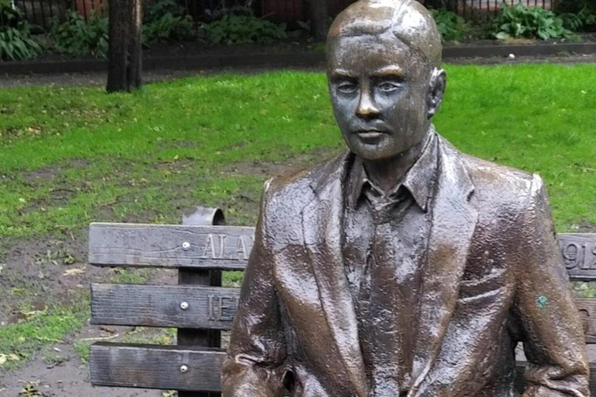 a statue of a man standing next to a park bench