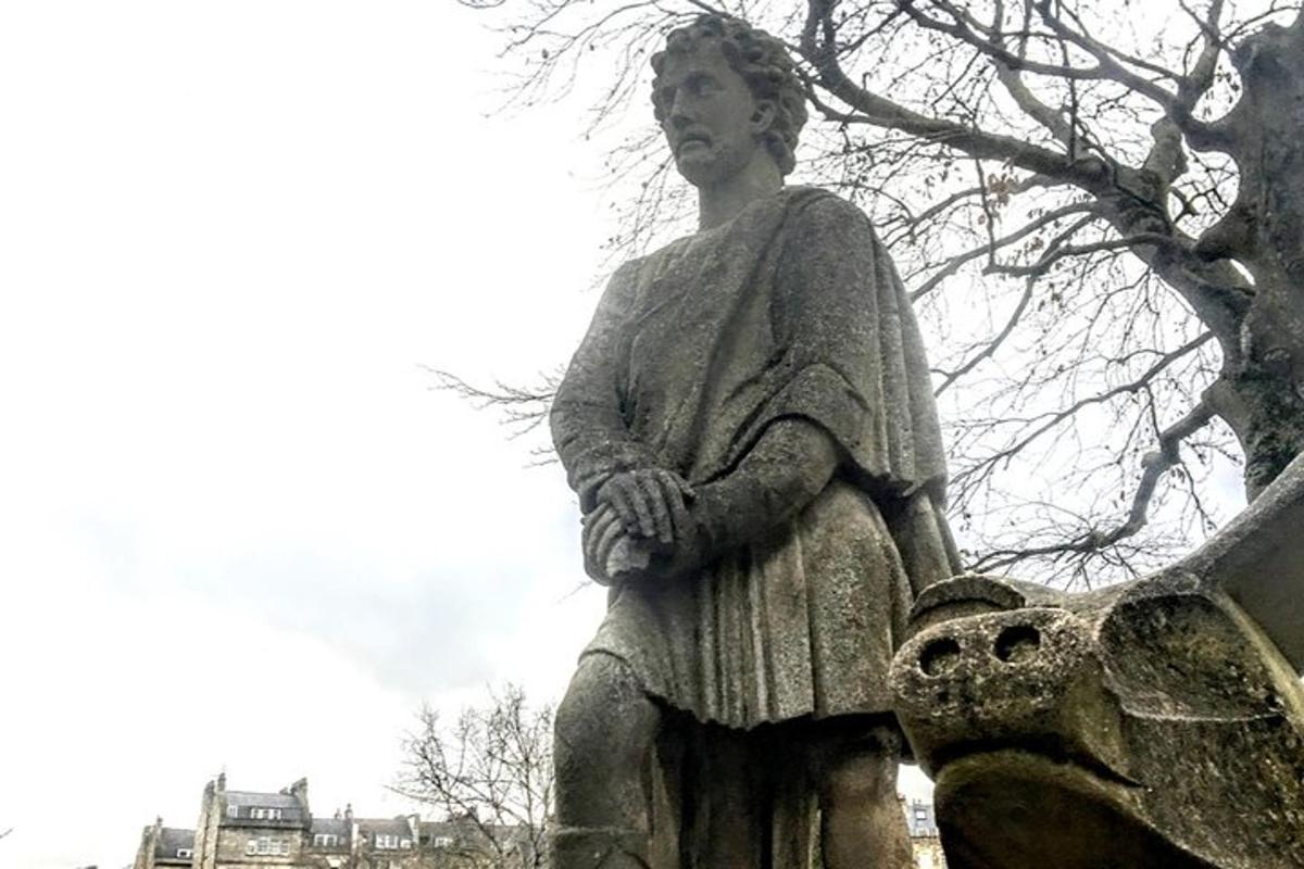 Una estatua de una mujer sentada sobre una estatua de pájaro.