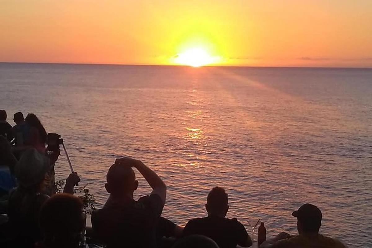 un gruppo di persone che guardano il tramonto sull'oceano