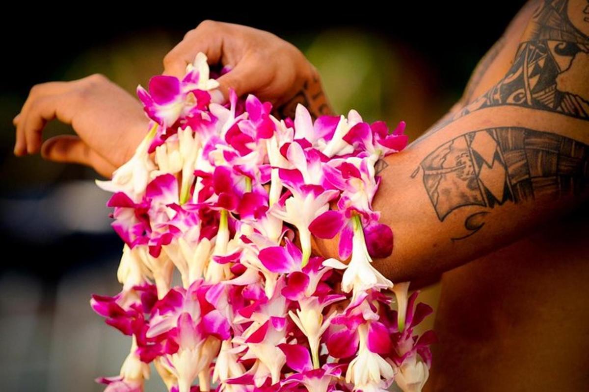 um homem com tatuagens no braço segurando um buquê de flores