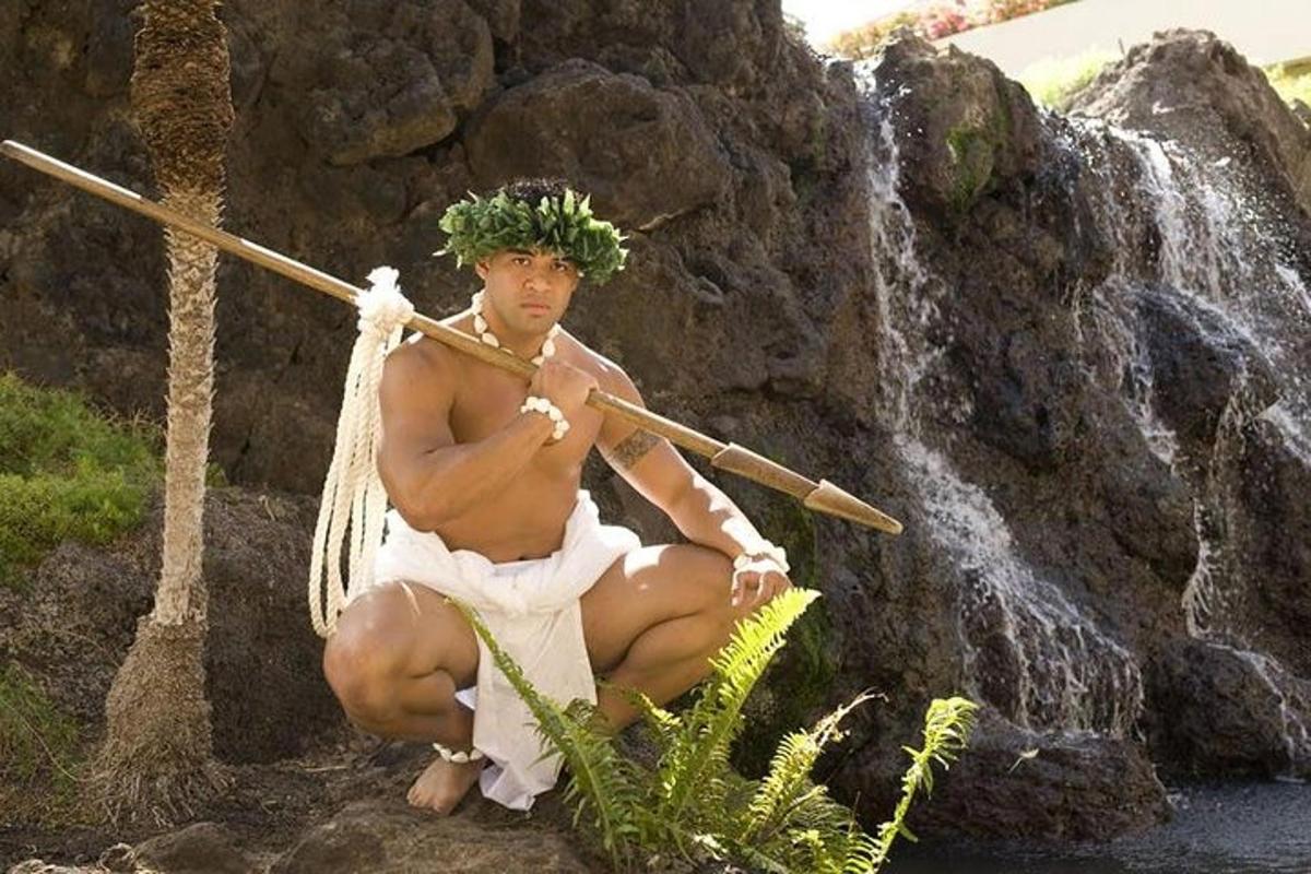 a statue of a man sitting on a rock next to a waterfall