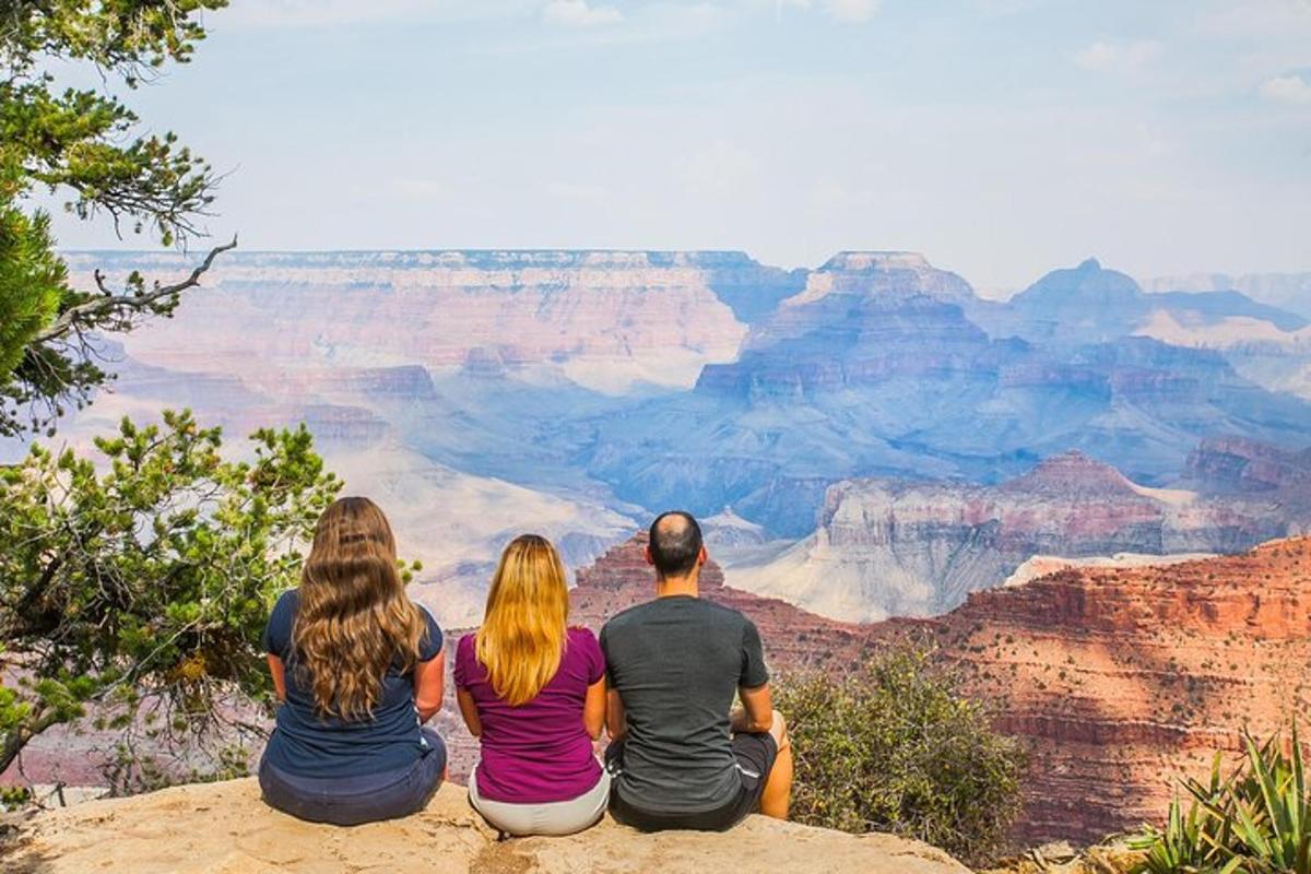 un gruppo di persone sedute sul bordo del Grand Canyon