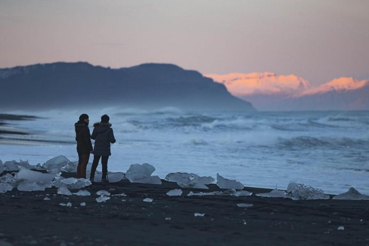 pár stojící na pláži a dívající se na oceán
